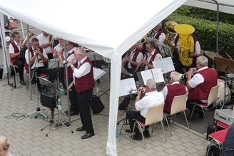 Blasorchester in roten Westen unter Pavillon mit Sänger und Tuben