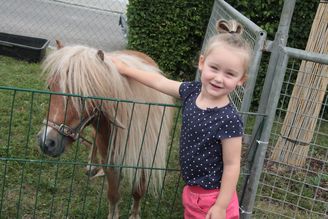 Mädchen streichelt kleines Pony mit langer blonder Mähne