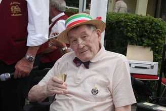 Älterer Mann mit Strohhut und Sektglas bei Fest